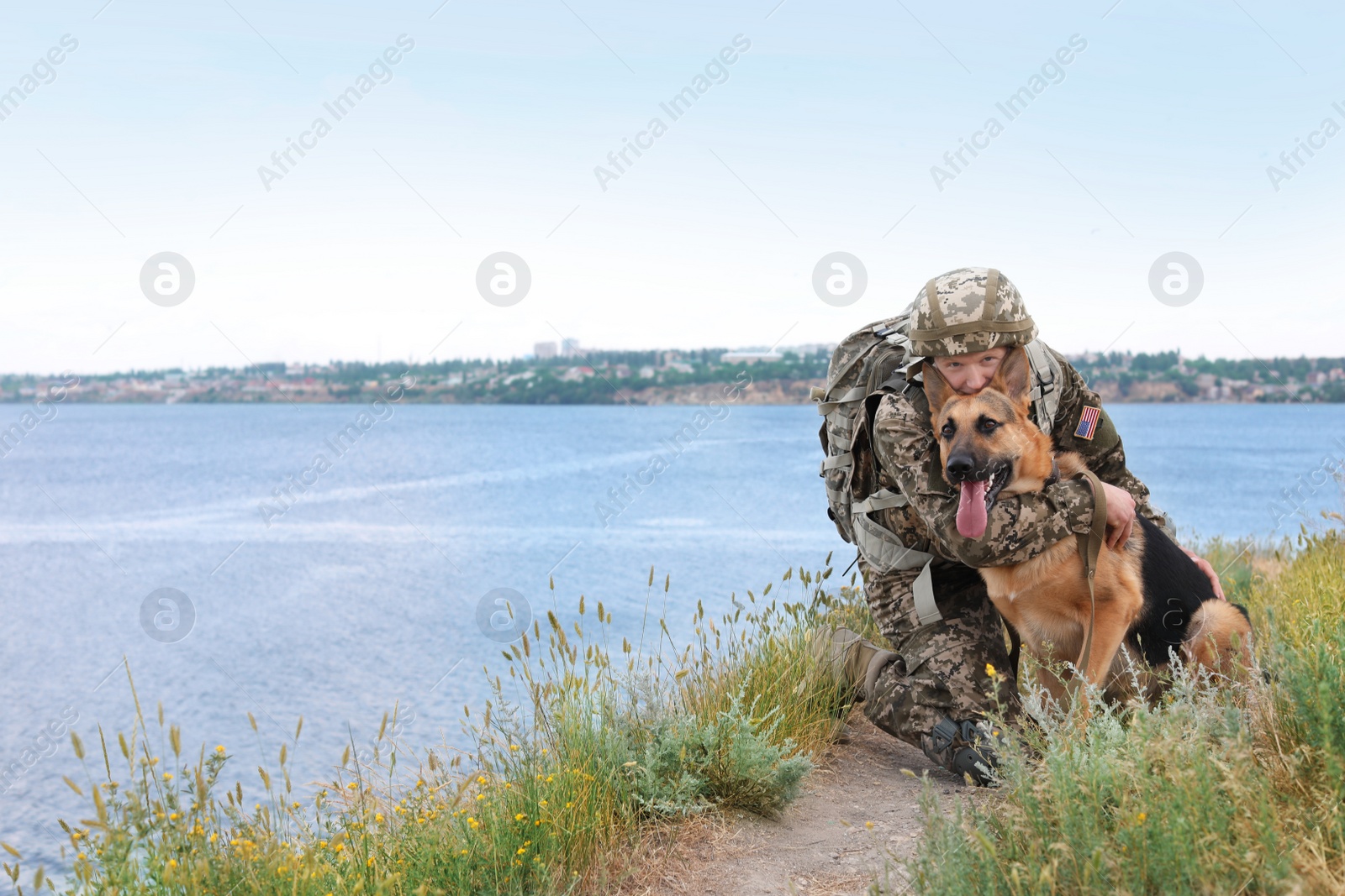 Photo of Man in military uniform with German shepherd dog near river