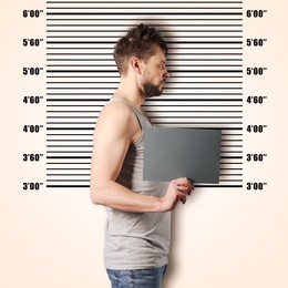 Image of Criminal mugshot. Arrested man with blank card against height chart