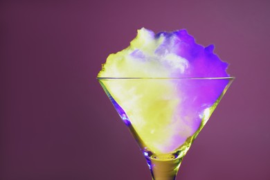 Photo of Beautiful martini glass with cotton candy on purple background, closeup. Space for text