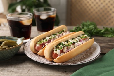 Photo of Delicious hot dogs with onion, chili pepper and sauce served on wooden table