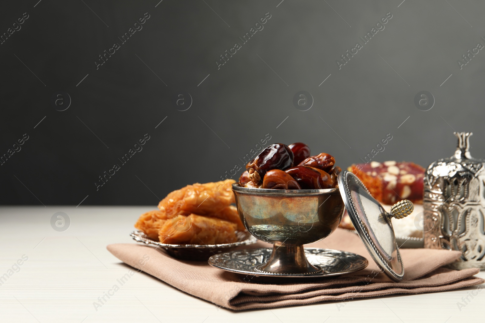 Photo of Tea, date fruits, Turkish delight and baklava dessert served in vintage tea set on white wooden table, space for text