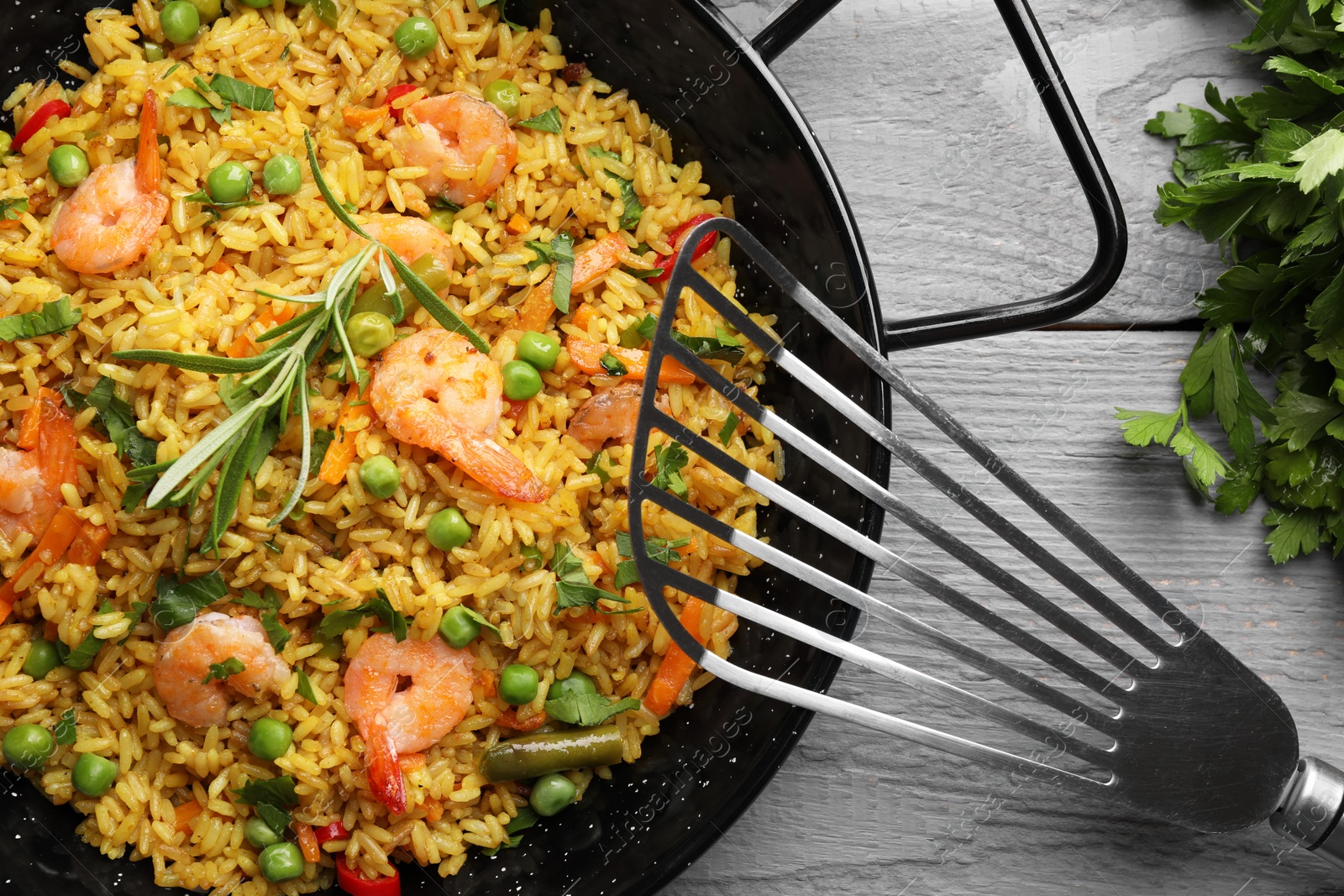 Photo of Tasty rice with shrimps and vegetables served on grey wooden table, flat lay