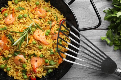 Tasty rice with shrimps and vegetables served on grey wooden table, flat lay