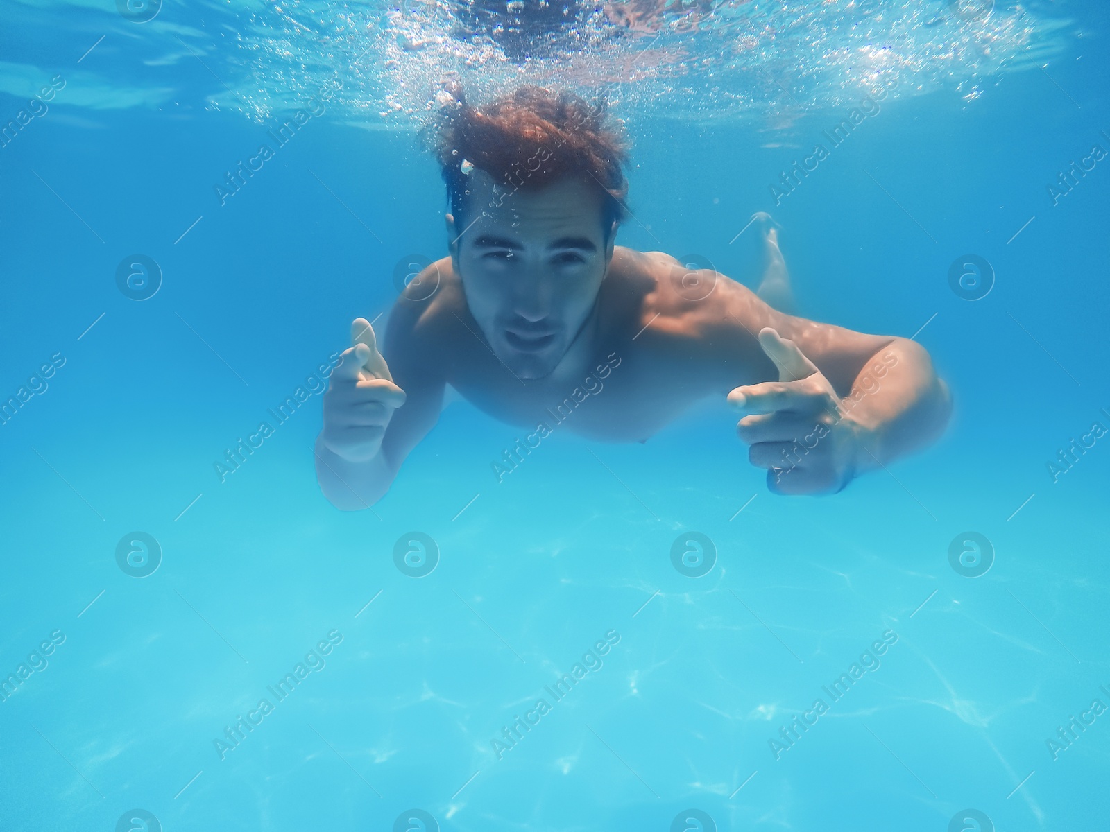 Photo of Handsome young man swimming in pool, underwater view