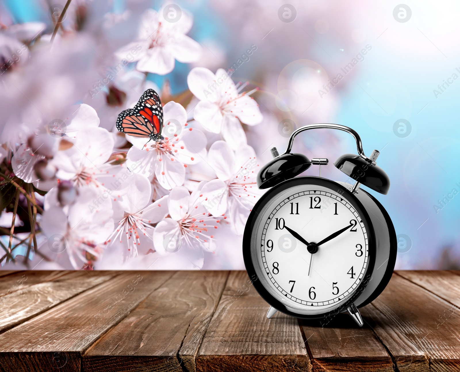 Image of Black alarm clock on wooden table, space for text. Daylight saving time (Spring forward)