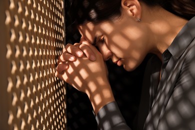 Photo of Repentant woman during confession near wooden partition in booth
