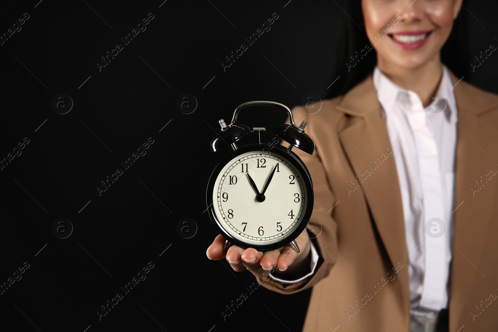 Photo of Businesswoman holding alarm clock on black background, closeup with space for text. Time management