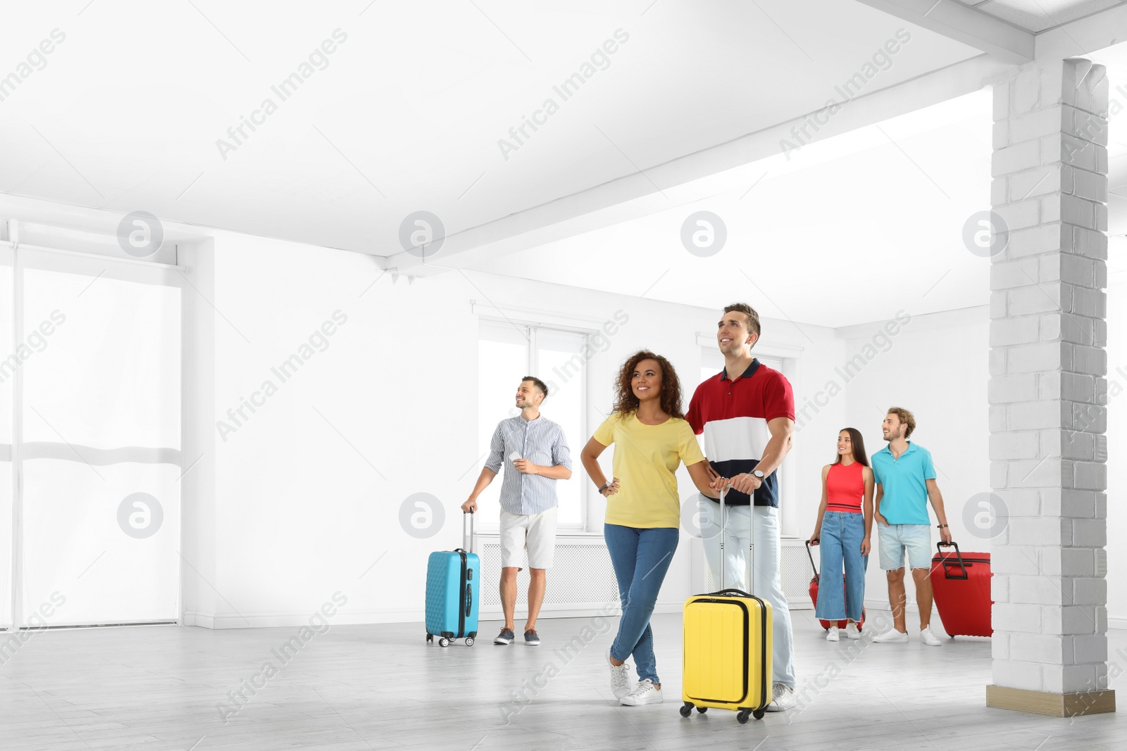 Photo of Group of young people with suitcases in light room