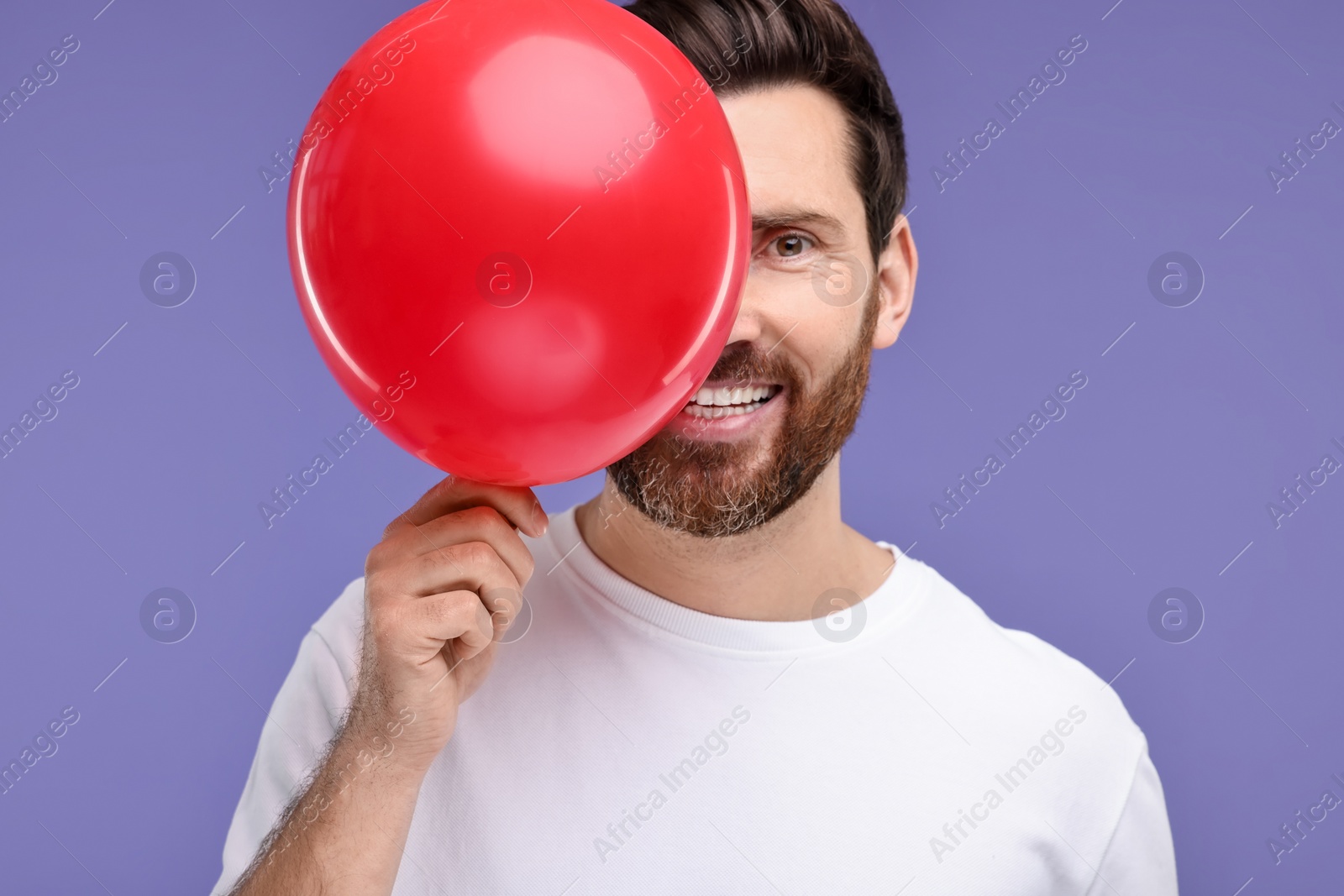 Photo of Happy man with red balloon on purple background