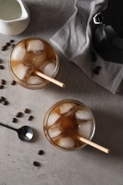 Photo of Refreshing iced coffee with milk in glasses, beans and spoon on gray table, flat lay