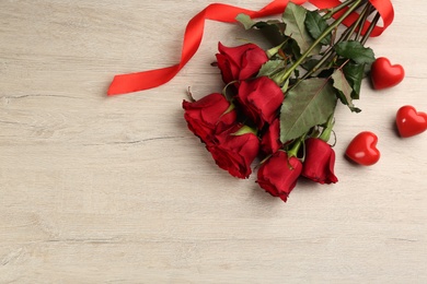 Photo of Beautiful red roses and decorative hearts on white wooden background, flat lay with space for text. Valentine's Day celebration