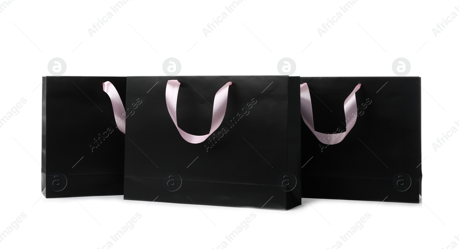 Photo of Paper shopping bags with ribbon handles on white background. Mockup for design