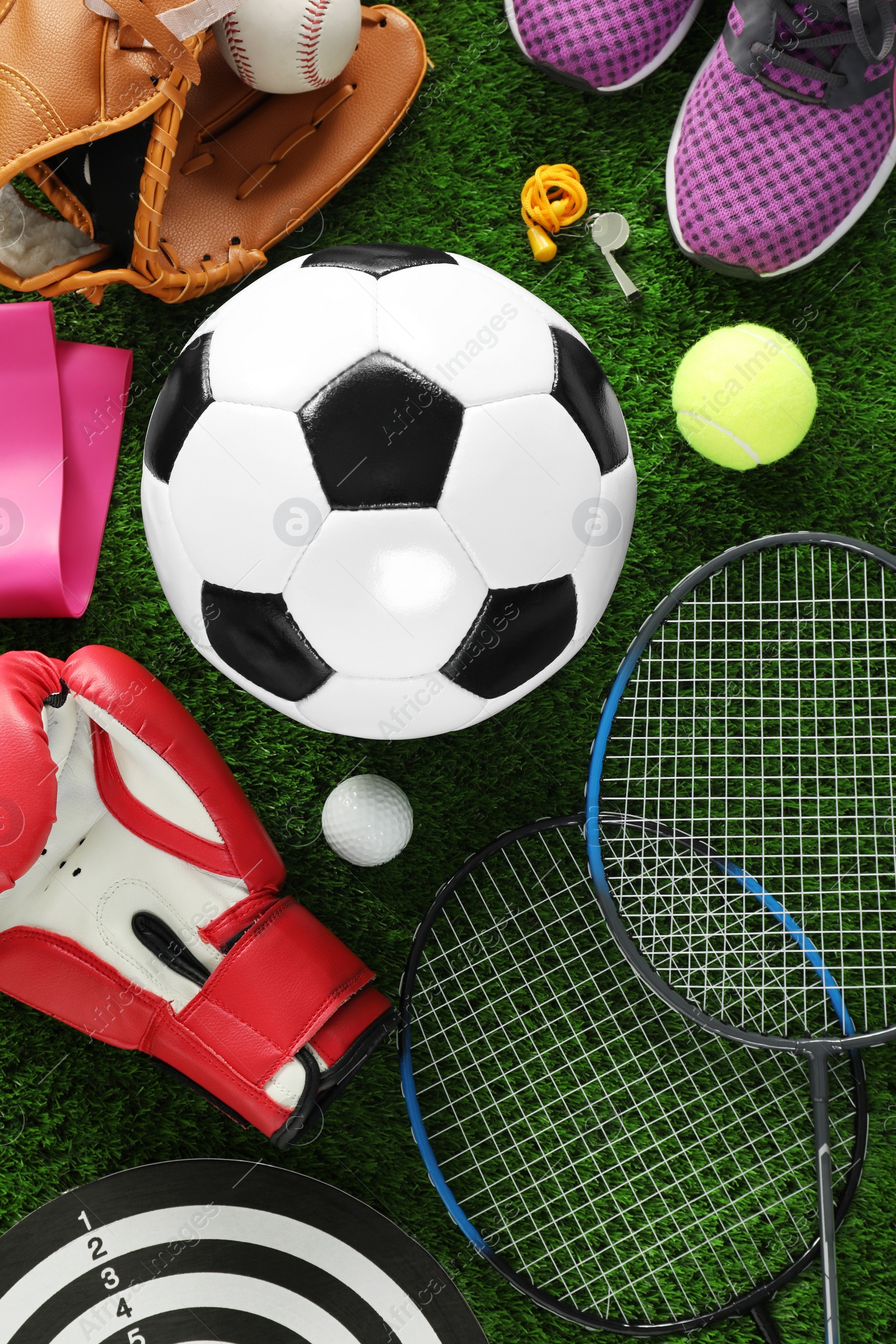 Photo of Different sport equipment on green grass, flat lay. Space for text