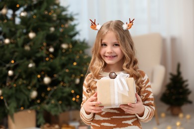 Photo of Portrait of cute smiling girl with Christmas gift at home