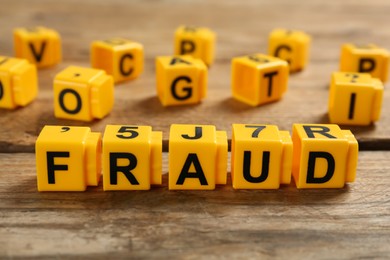 Word Fraud of yellow cubes with letters on wooden background