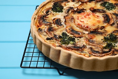 Photo of Delicious quiche with mushrooms on light blue wooden table, closeup