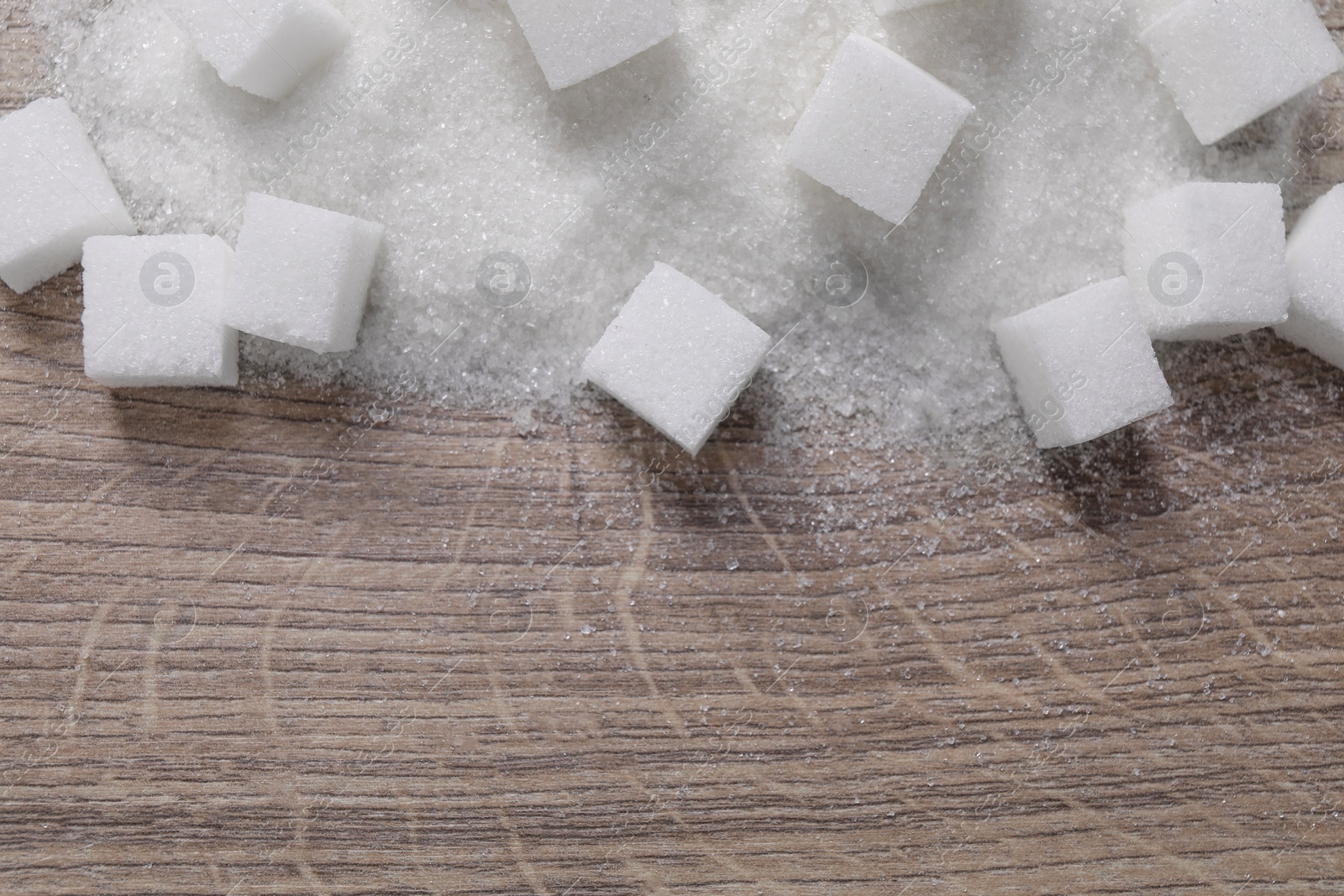 Photo of Different types of white sugar on wooden table, top view. Space for text