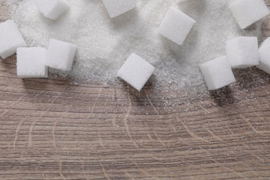 Different types of white sugar on wooden table, top view. Space for text