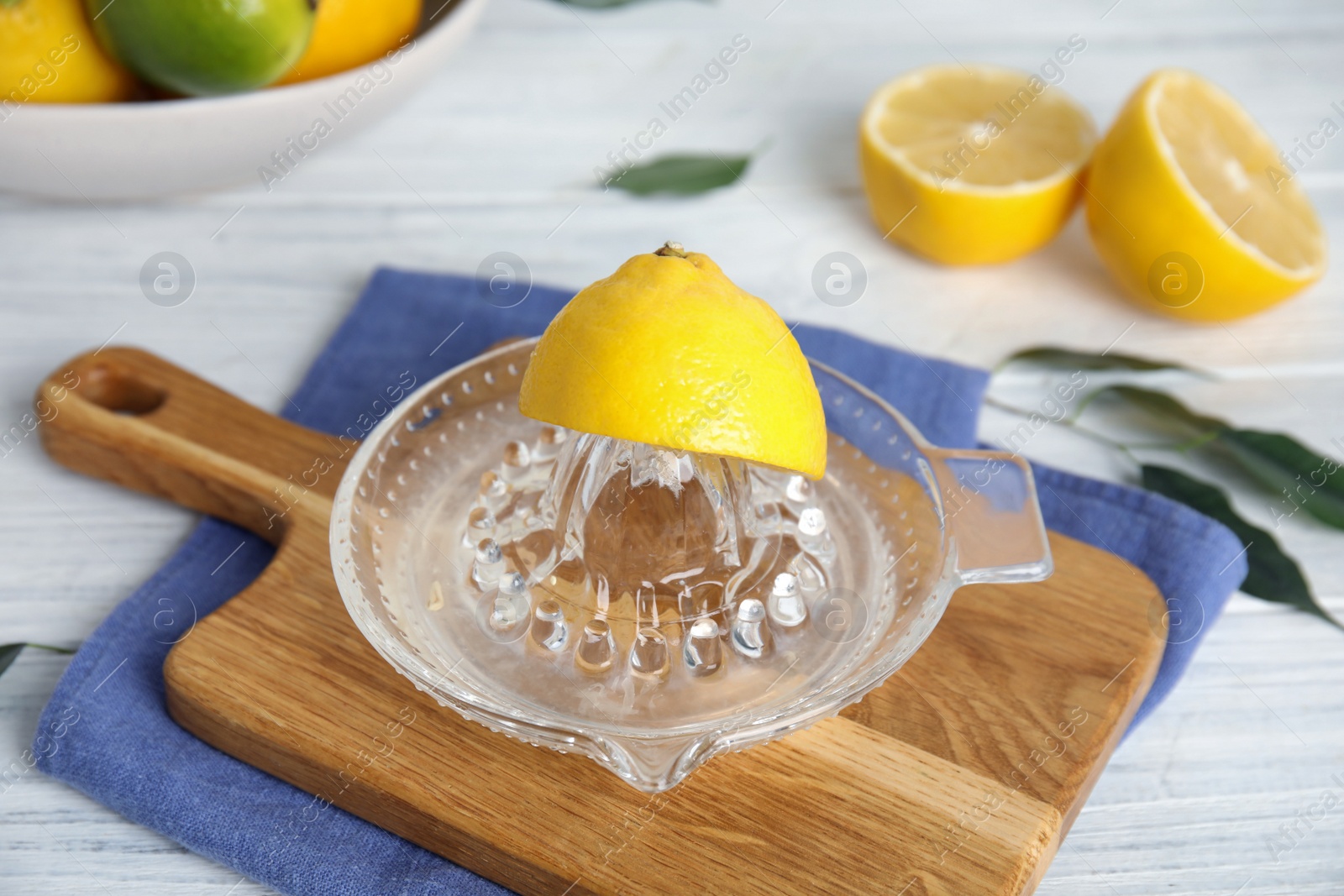 Photo of Glass squeezer and fresh lemons on white wooden table