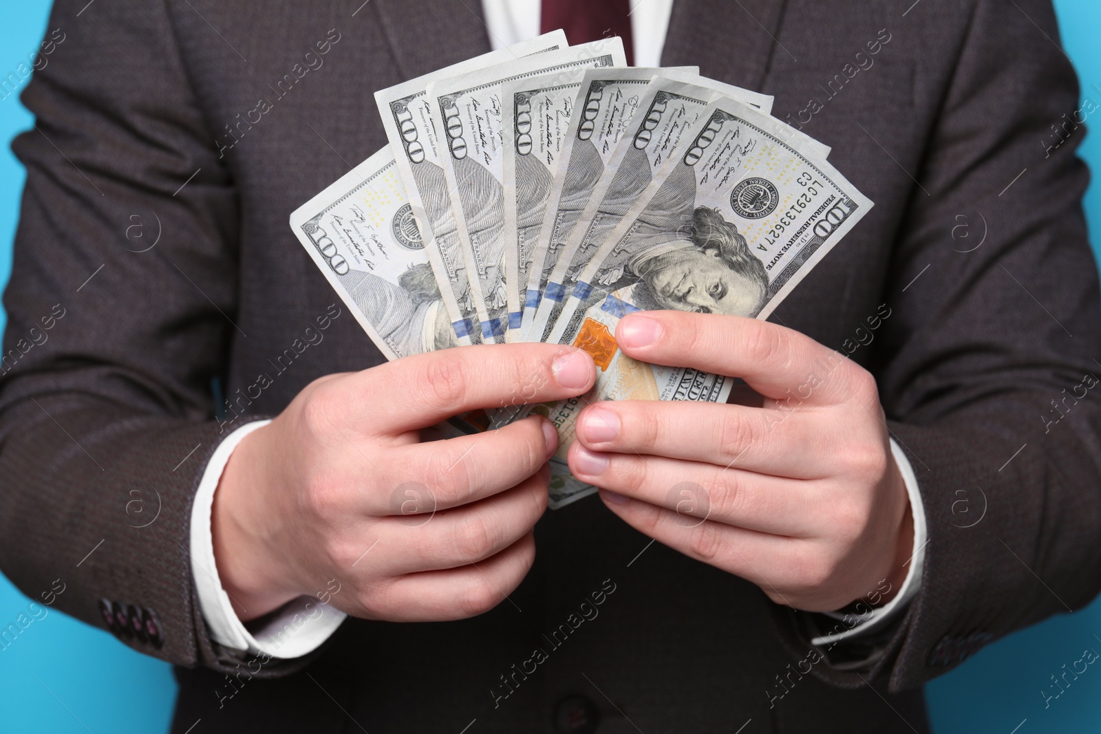 Photo of Man holding money on light blue background, closeup. Currency exchange
