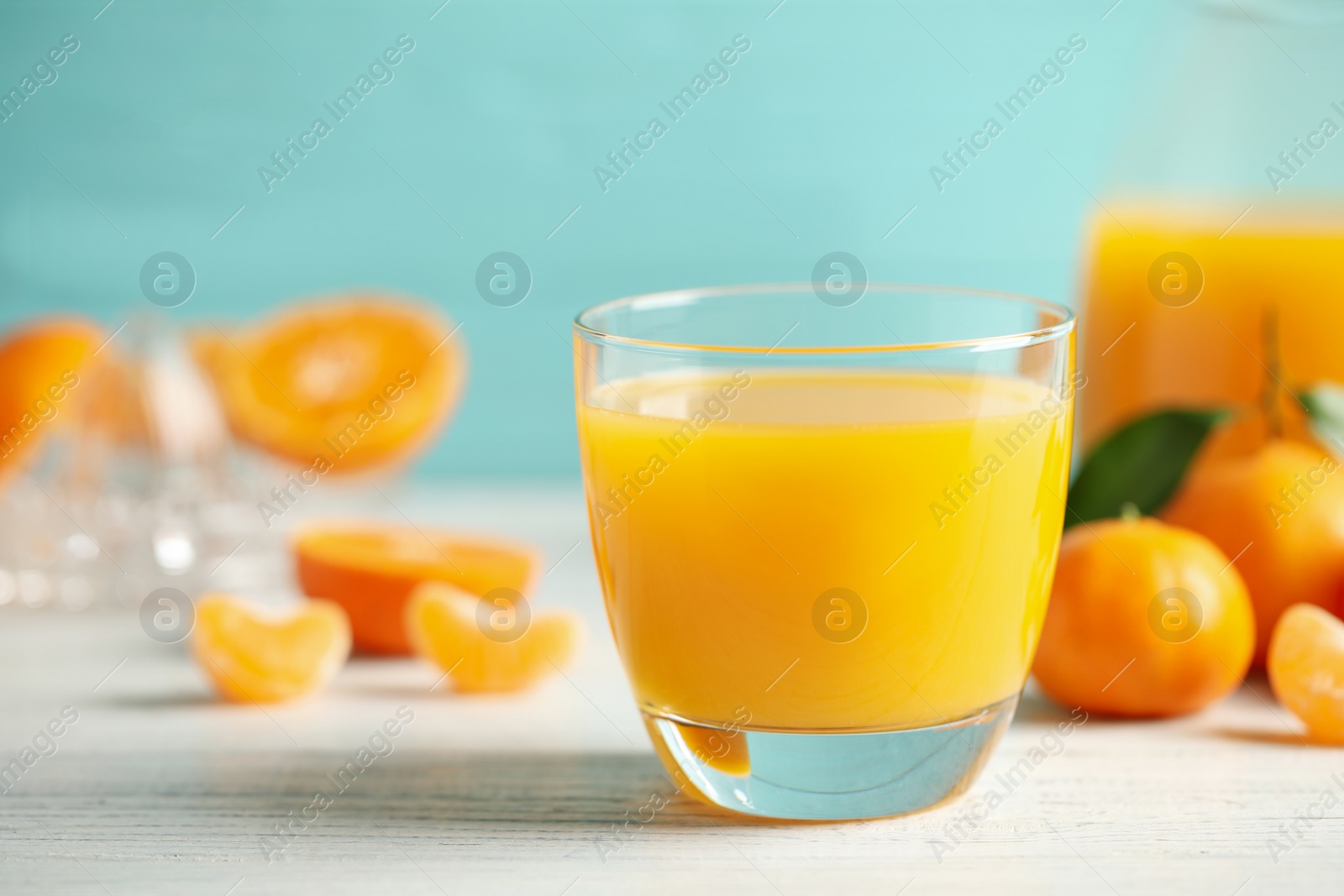 Photo of Glass of fresh tangerine juice and fruits on white wooden table