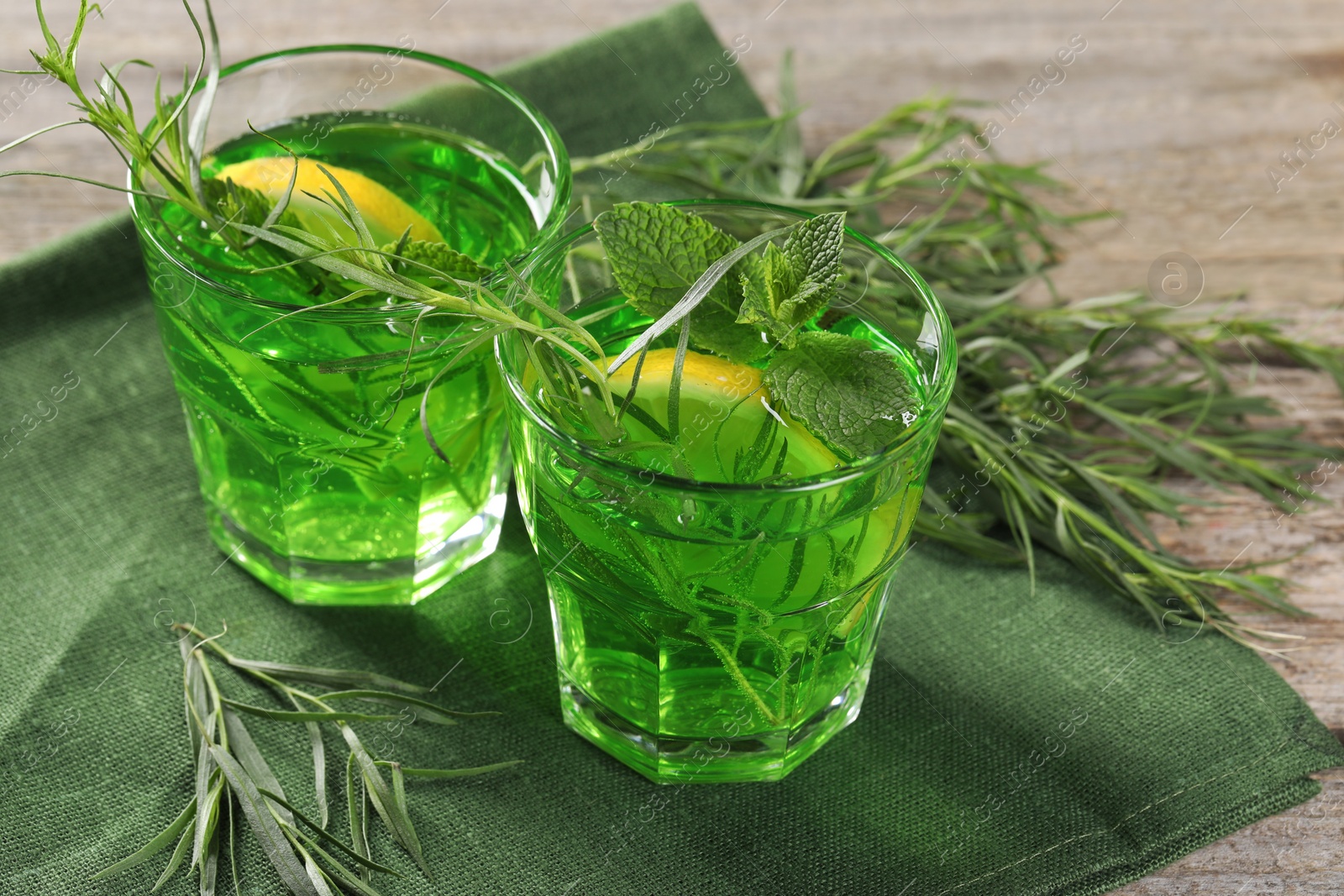 Photo of Glasses of refreshing tarragon drink with lemon slices on wooden table
