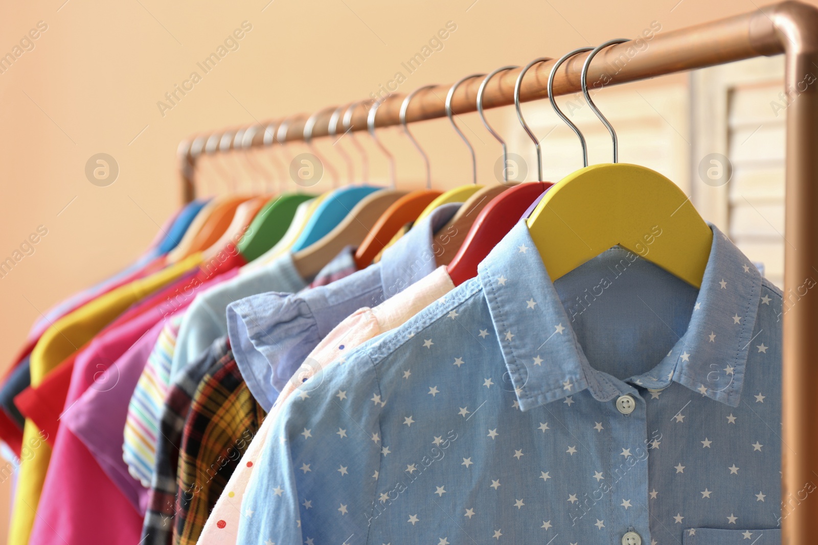 Photo of Different child's clothes hanging on rack indoors, closeup