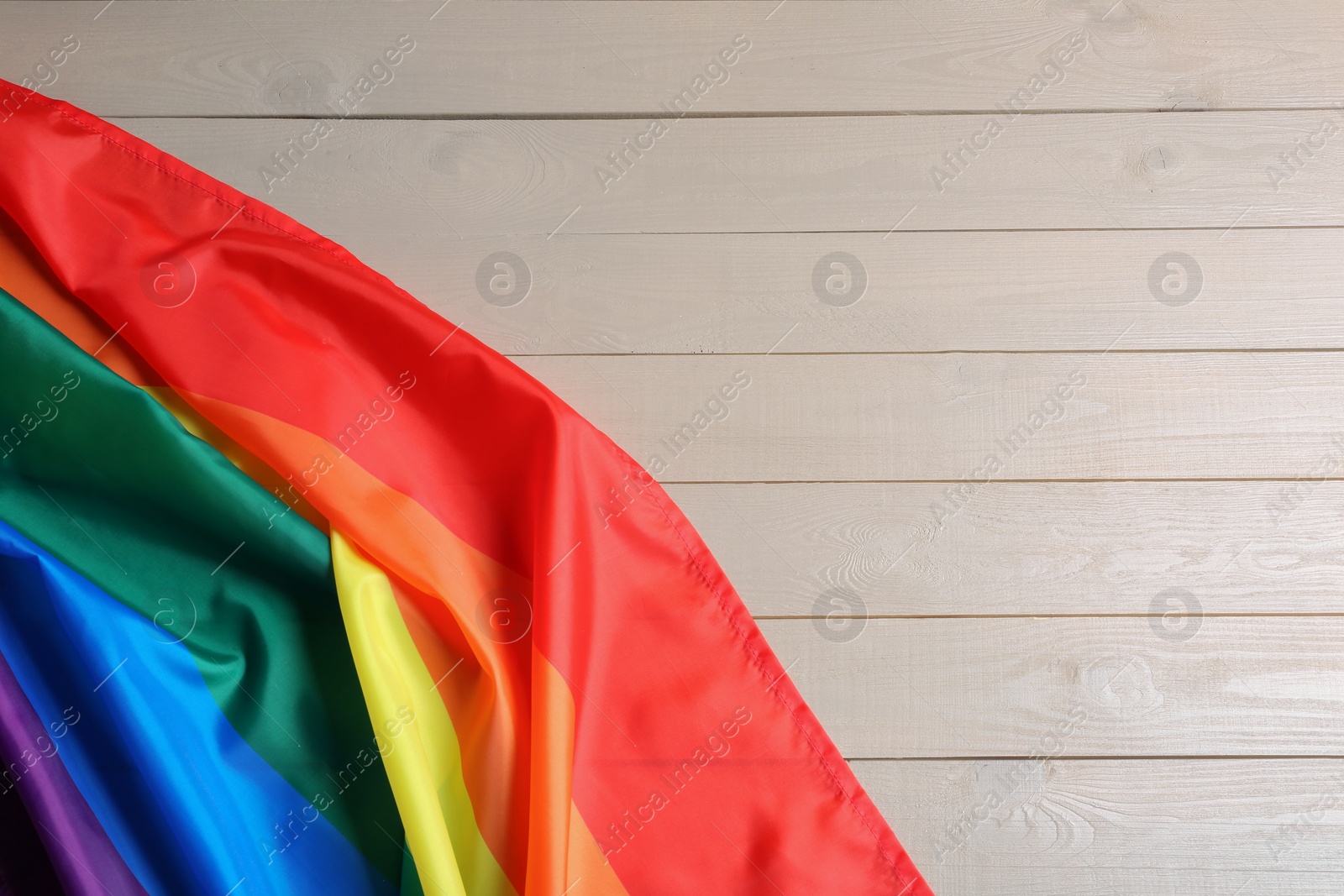 Photo of Bright rainbow gay flag on wooden background, top view with space for text. LGBT community