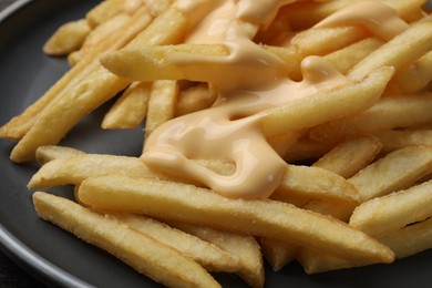 Delicious french fries with cheese sauce on plate, closeup