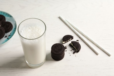 Photo of Glass of milk with chocolate cookies on wooden background, space for text