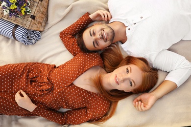 Photo of Happy young couple lying on picnic blanket, top view