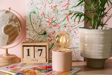 Photo of Modern night lamp and decor on table near pink wall