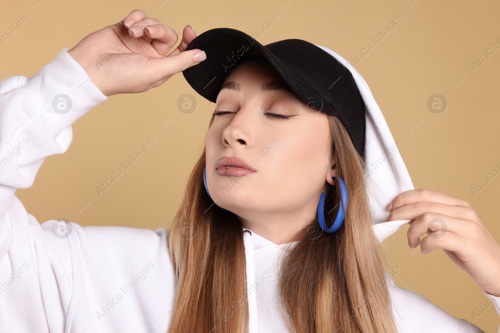 Photo of Young woman with lip piercing on beige background