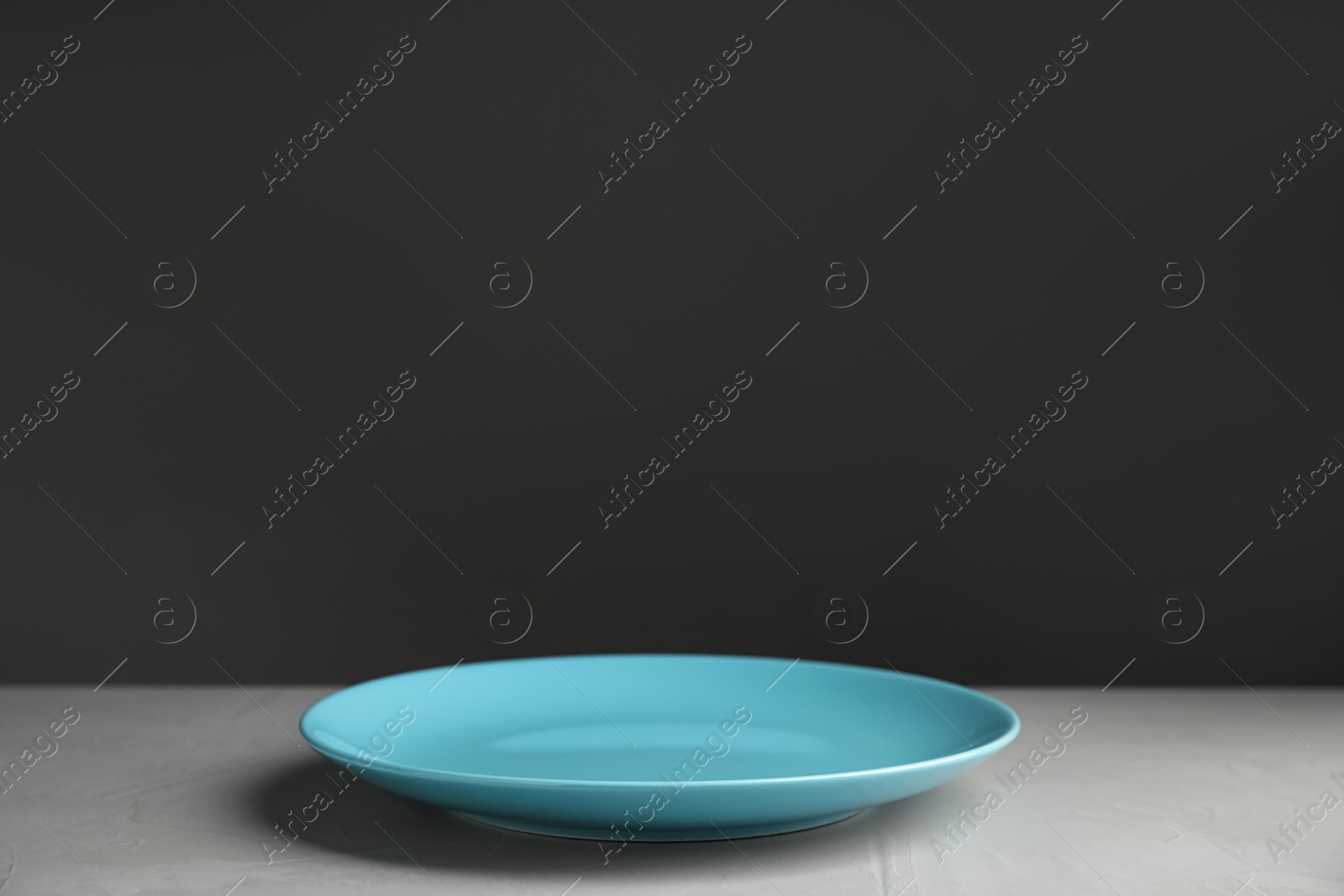 Photo of Empty blue plate on light grey table. Space for text