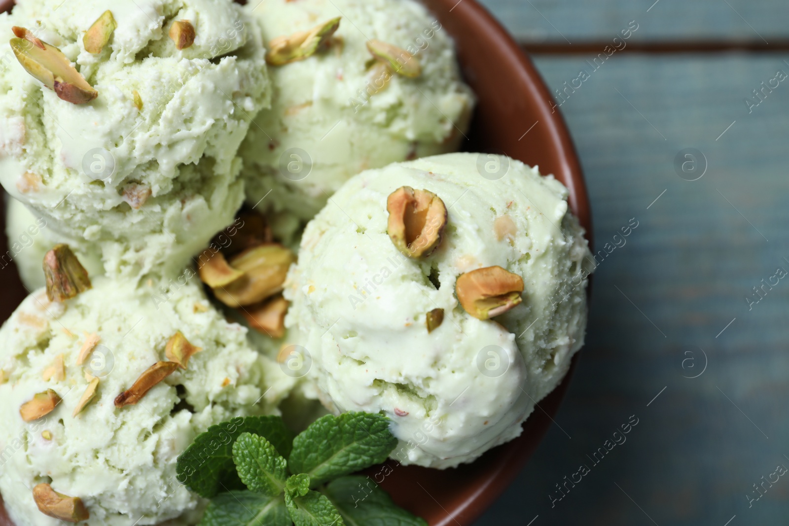 Photo of Delicious pistachio ice cream in bowl on blue table, top view