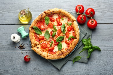 Delicious Margherita pizza and ingredients on gray wooden table, flat lay