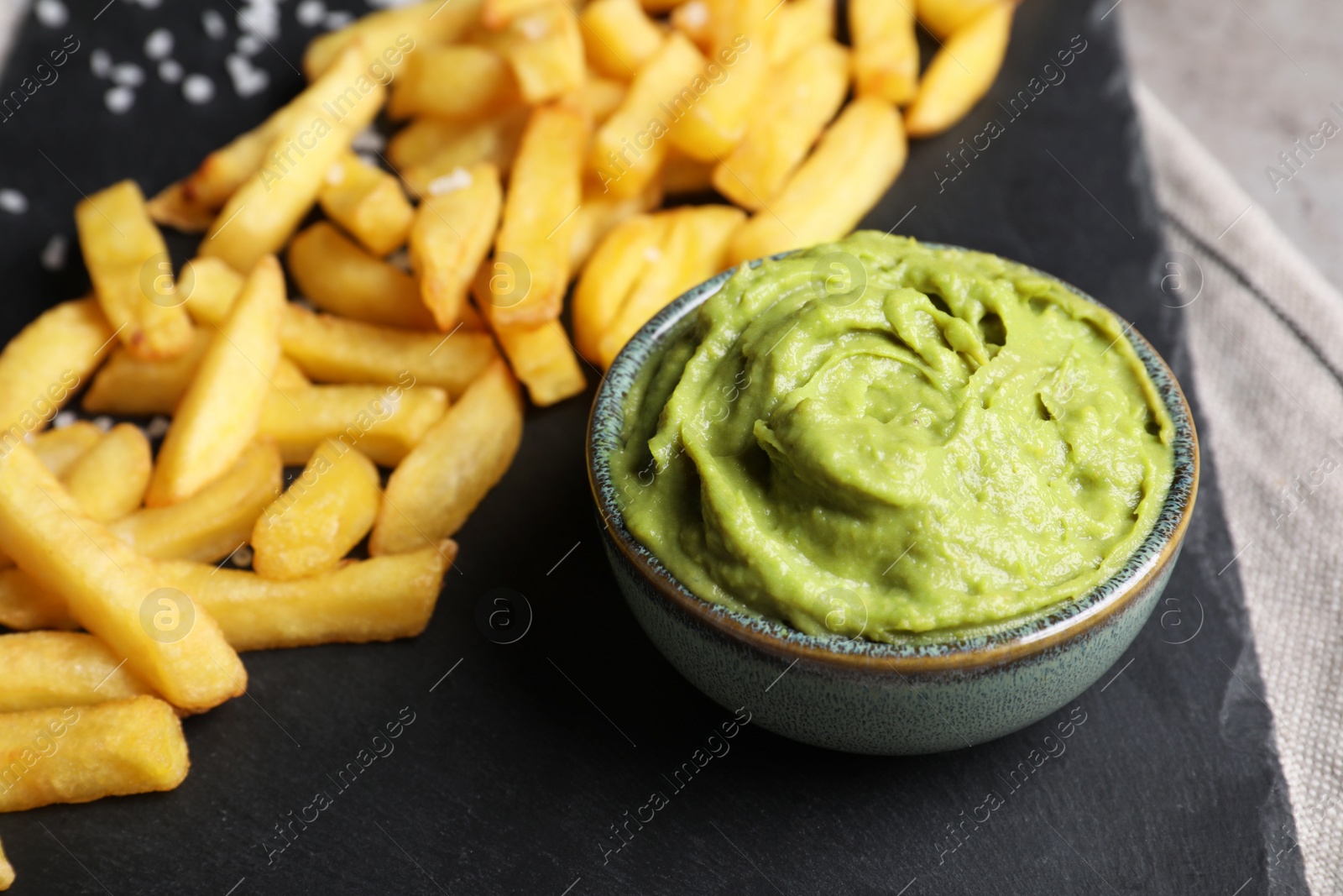 Photo of French fries and avocado dip on serving board, closeup