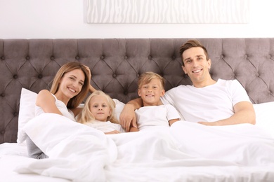 Happy family in bed with pillows at home. Weekend morning