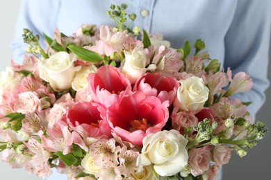 Woman with beautiful bouquet of fresh flowers on light background, closeup