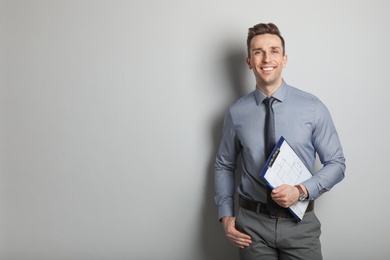 Photo of Male real estate agent with clipboard on grey background