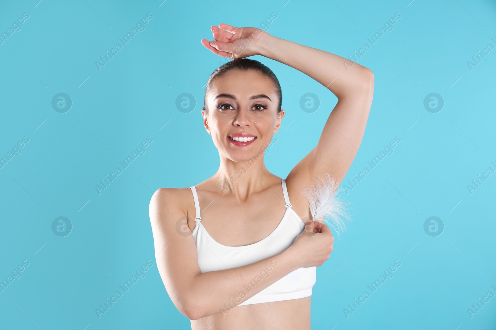 Photo of Woman touching armpit with feather on blue background. Epilation procedure