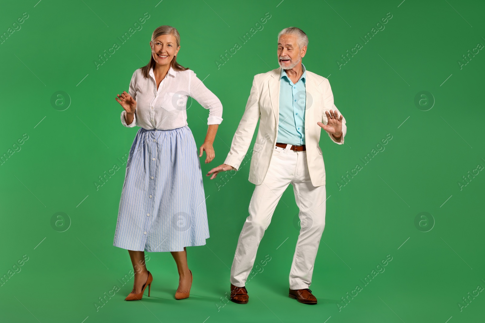 Photo of Senior couple dancing together on green background