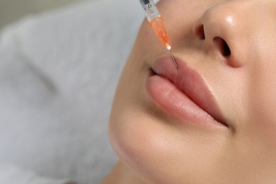Photo of Young woman getting facial injection in clinic, closeup and space for text. Cosmetic surgery