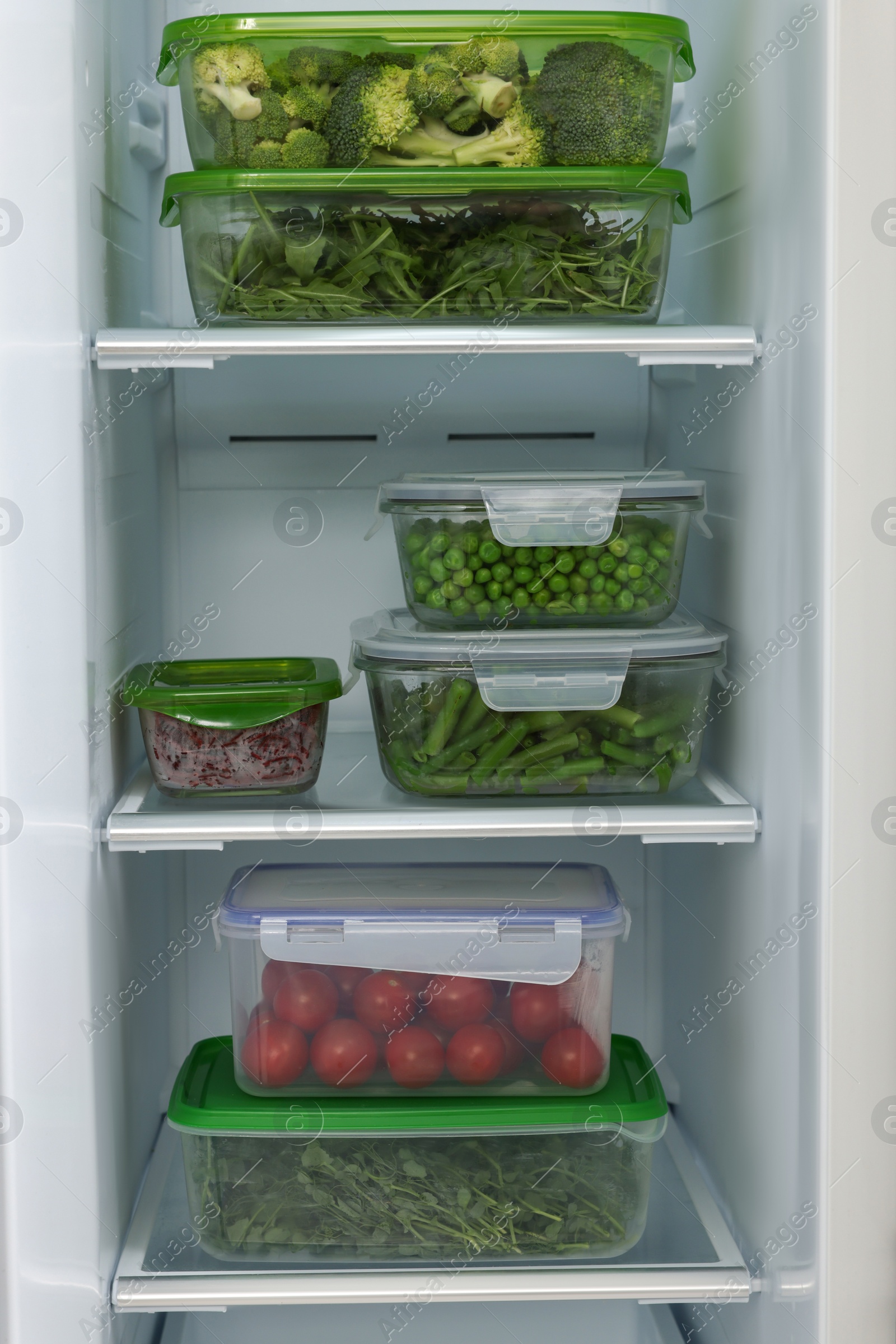 Photo of Glass and plastic containers with different fresh products in fridge. Food storage