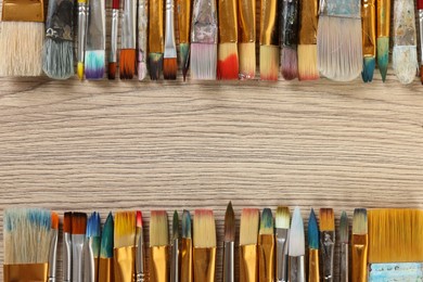 Photo of Set of different paintbrushes on wooden table, flat lay. Space for text