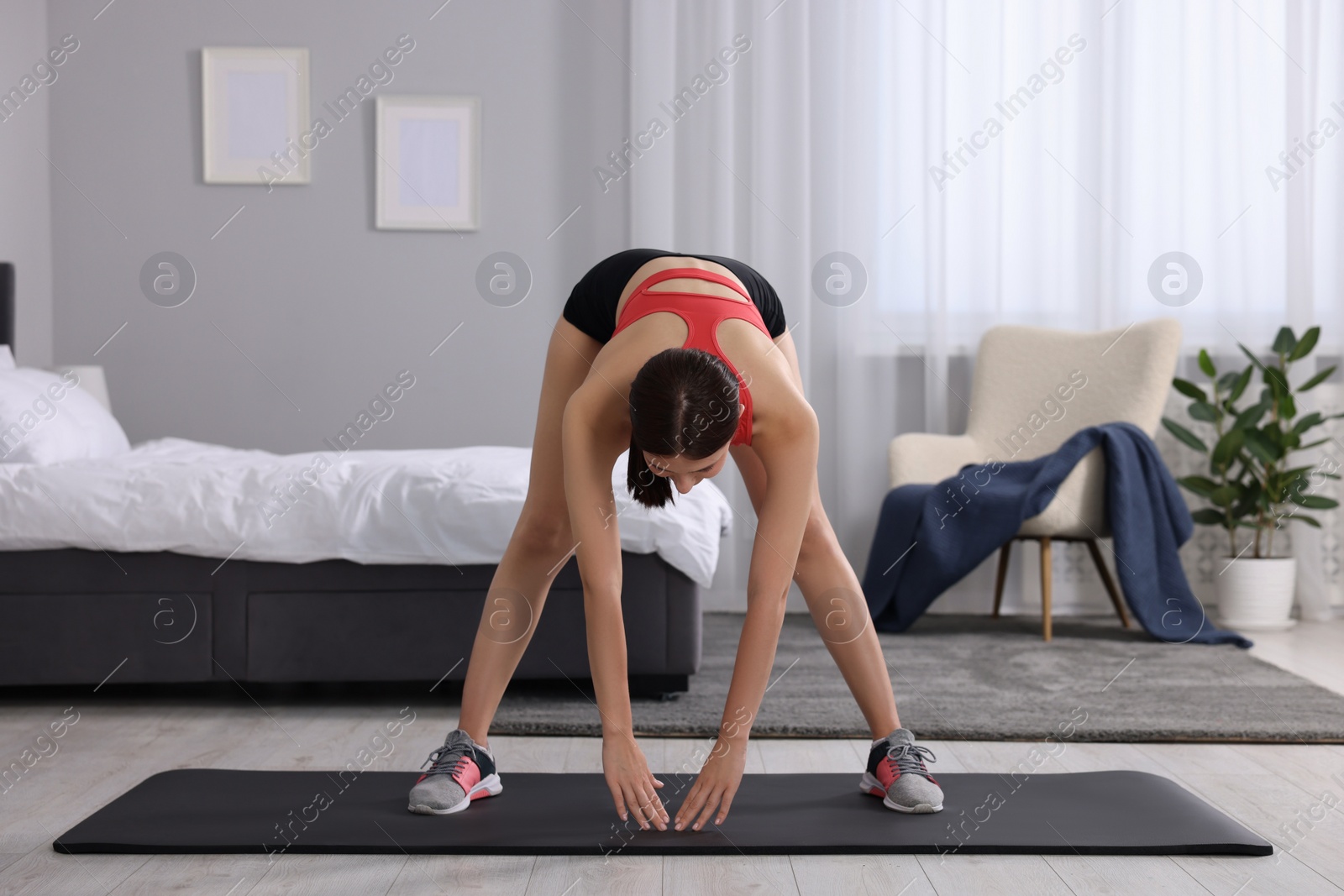 Photo of Morning routine. Sporty woman stretching at home