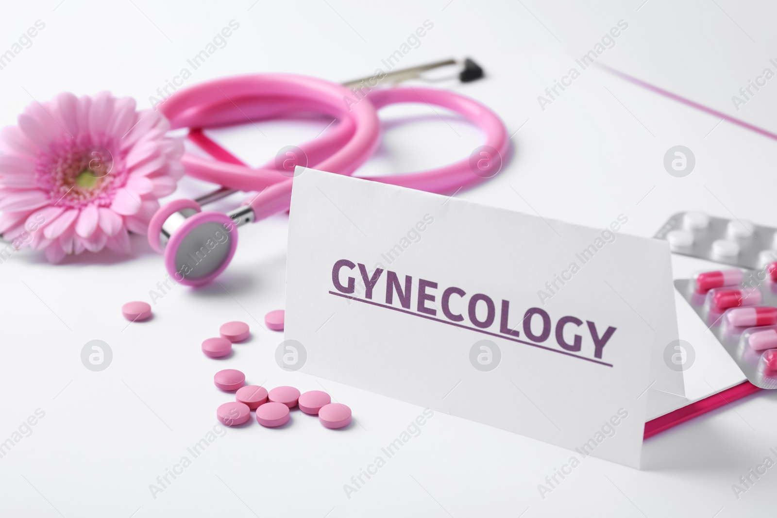 Photo of Card with word Gynecology, pills, stethoscope and flower on white background