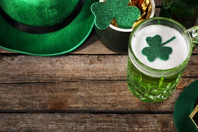 Photo of St. Patrick's day party. Green beer, leprechaun hat, pot of gold and decorative clover leaves on wooden table, above view. Space for text