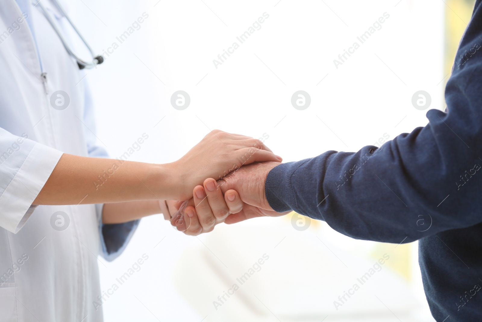 Photo of Doctor holding elderly patient hand in hospital, closeup