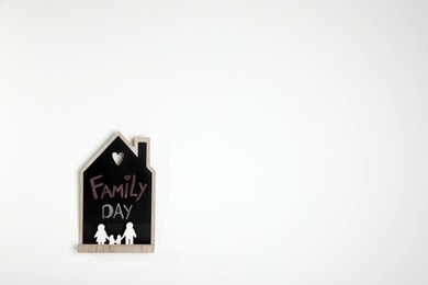 Photo of House shaped blackboard with phrase Family day and figures on white background. Space for text